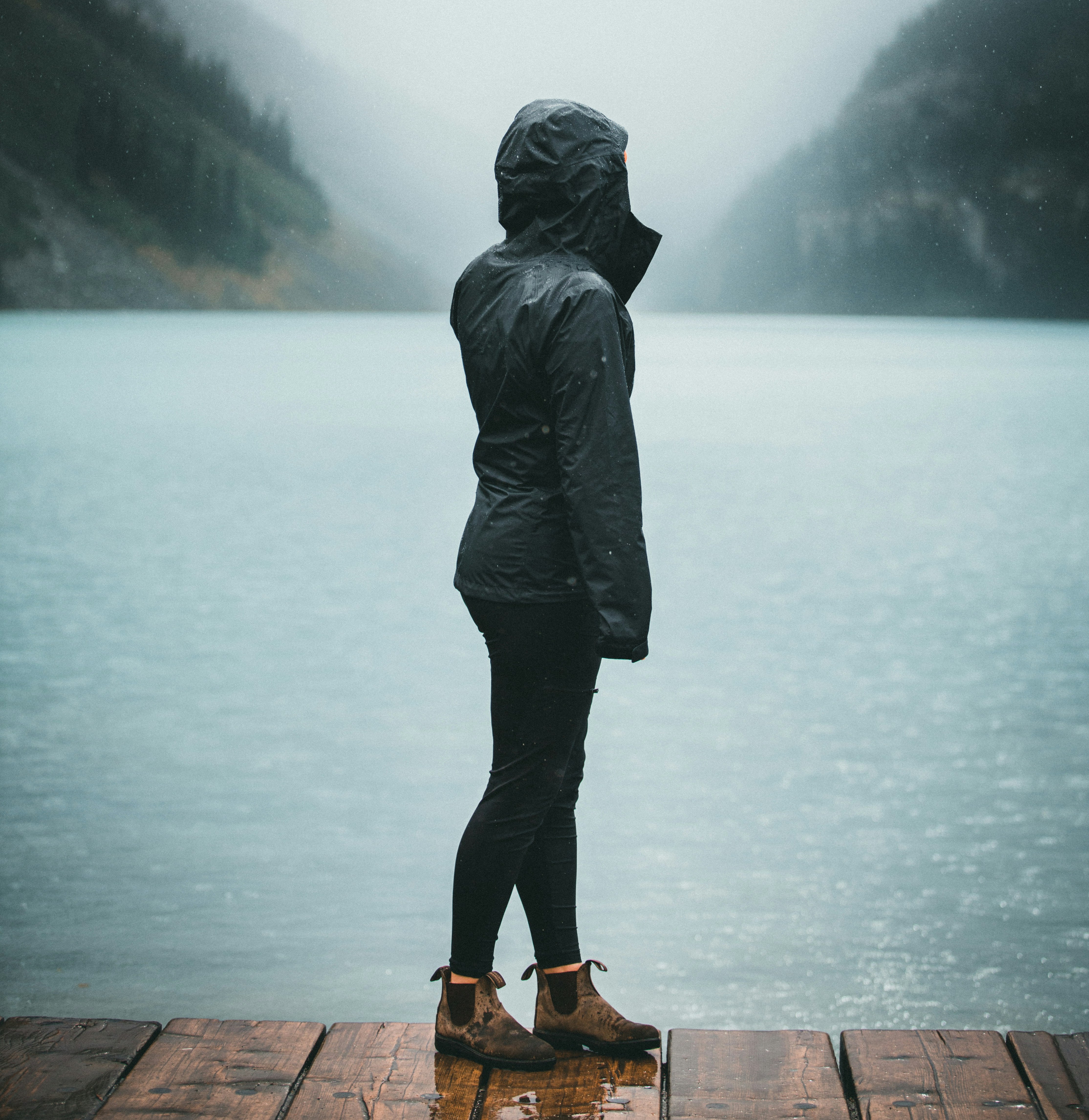 woman standing on pier with mountains in background